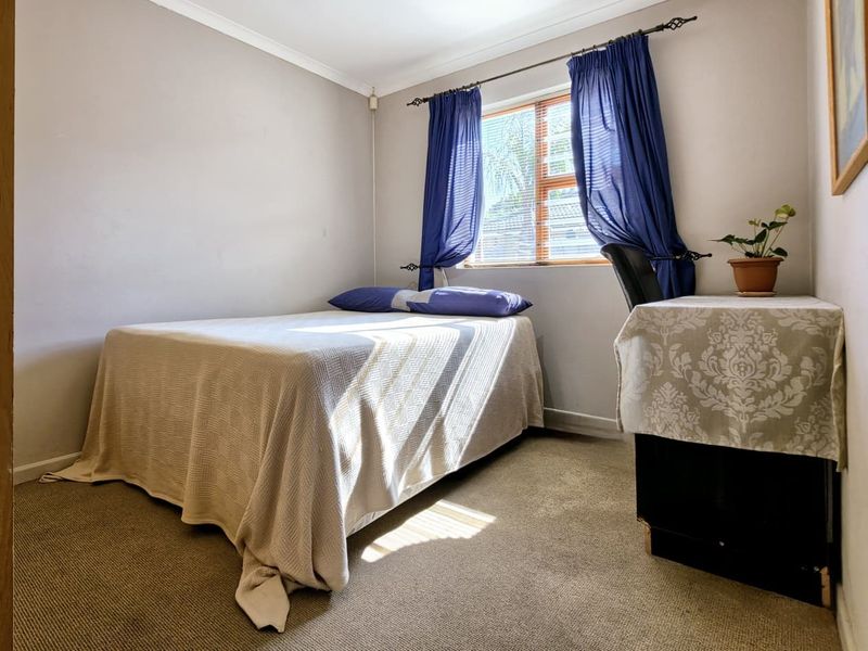 A standard bedroom featuring carpeted flooring, a window with a curtain rod, and coved ceiling detailing.