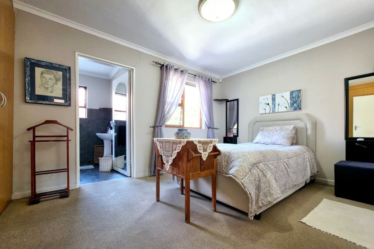A carpeted bedroom featuring a built-in cupboard and direct access to an en-suite bathroom with neutral wall tones.