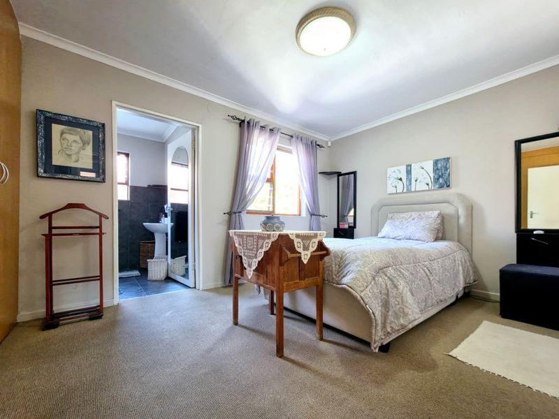 A carpeted bedroom featuring a built-in cupboard and direct access to an en-suite bathroom with neutral wall tones.