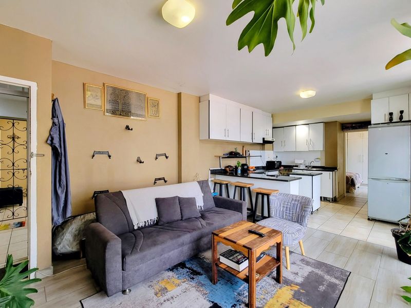 Open plan living area featuring a functional kitchen with white cabinetry, granite countertops, and a breakfast bar, seamlessly connected to the lounge space.