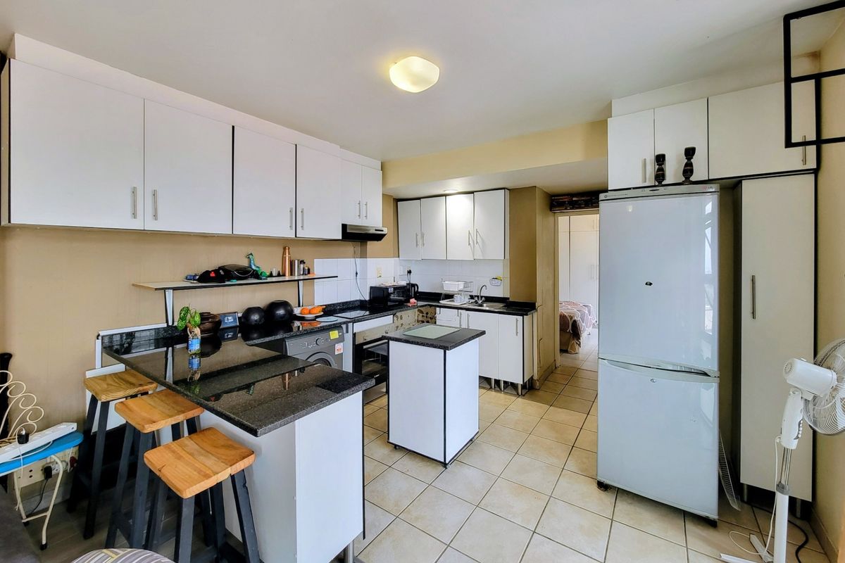 A functional kitchen featuring white cabinetry, dark granite countertops, tiled flooring, and an integrated extractor fan, offering a practical layout for daily use.