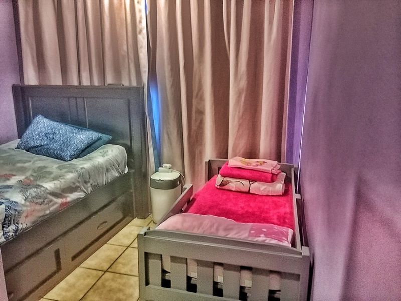 A bedroom featuring tiled flooring and neutral curtains, currently configured with multiple sleeping arrangements.