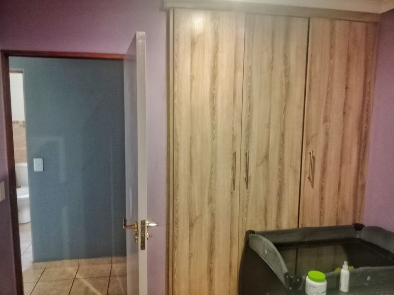 Bedroom featuring built-in wooden cupboards and direct access to an adjoining bathroom.
