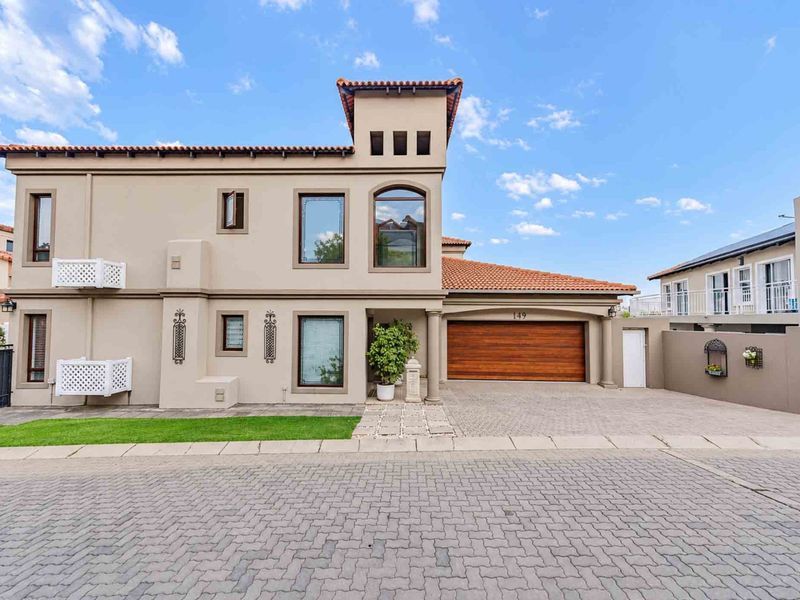 A well-maintained two-story residential property featuring a terracotta tiled roof, stucco exterior, and a double garage with a wooden door.