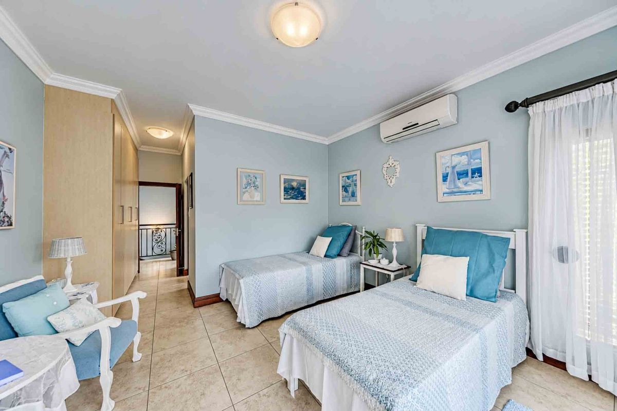 A well-maintained bedroom featuring tiled flooring, built-in cupboards, and a split-system air conditioning unit, offering a comfortable and functional living space.