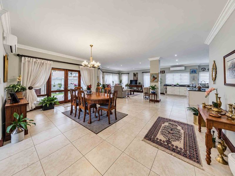 Spacious open-plan living and dining area featuring tiled floors, recessed lighting, split-system air conditioning, and a modern kitchen with a central island.