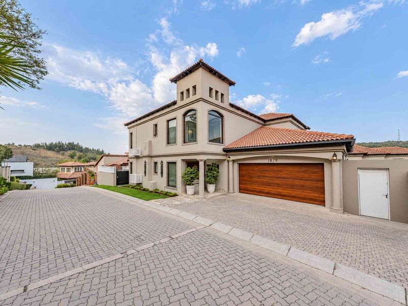 A well-maintained double-story residence featuring a paved driveway, double garage, and distinctive architectural tower design with arched windows.