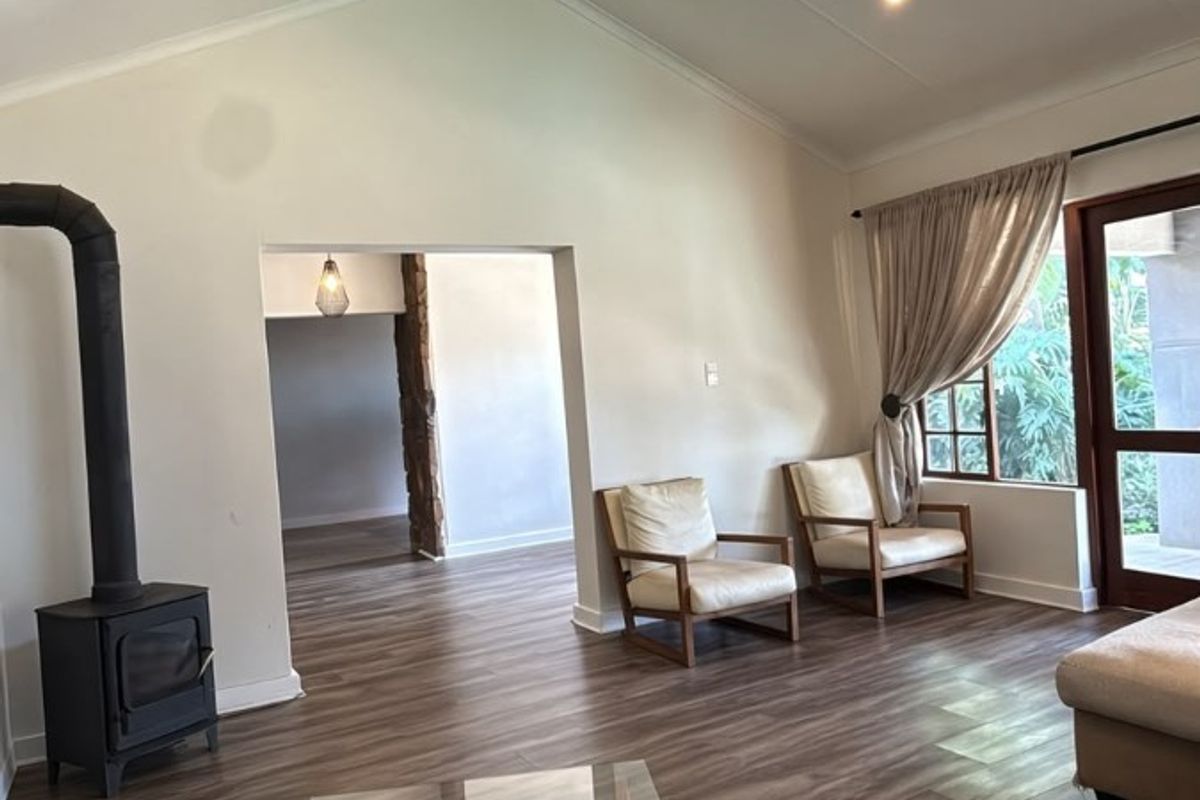 Spacious living room featuring a vaulted ceiling, wood-burning stove, and laminate flooring with direct access to the outdoor area.