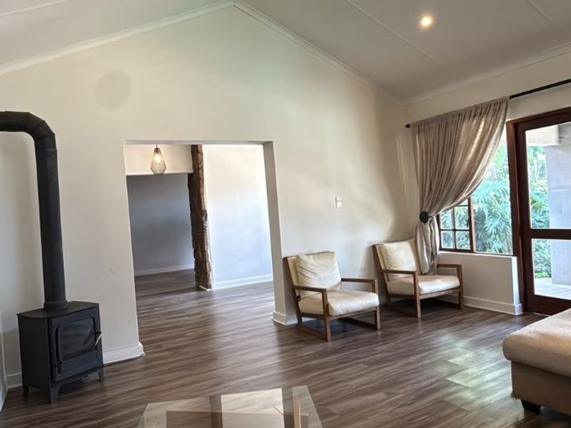 Spacious living room featuring a vaulted ceiling, wood-burning stove, and laminate flooring with direct access to the outdoor area.