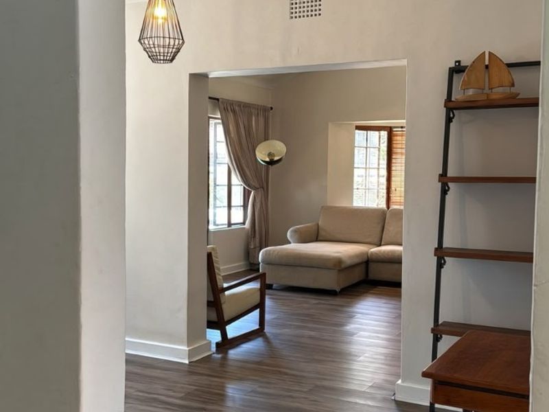A view through a doorway into a living area featuring modern laminate flooring and a contemporary pendant light fixture.