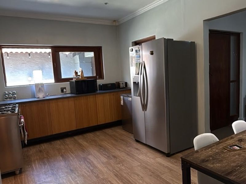 A functional kitchen featuring wood-look laminate flooring, built-in cabinetry with laminate countertops, and recessed lighting, offering a practical and well-lit workspace.