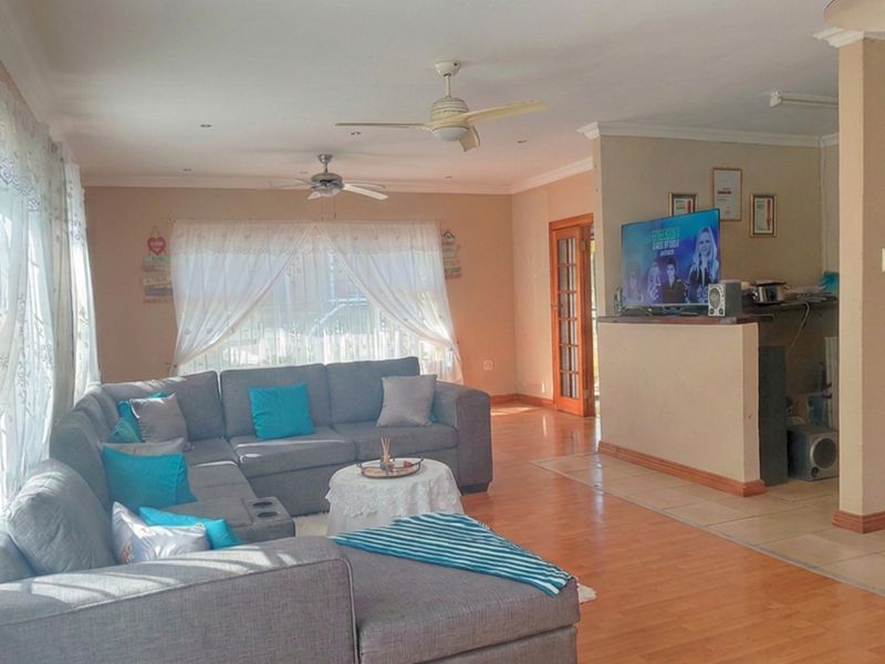Open plan living area featuring laminate flooring, ceiling fans, and a breakfast counter connecting to the kitchen space.