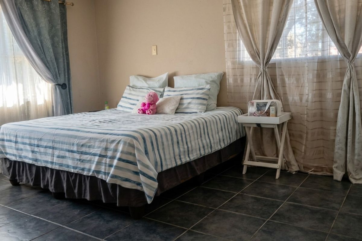 A bedroom featuring dark tiled flooring and dual window treatments, providing a neutral base for interior design updates.