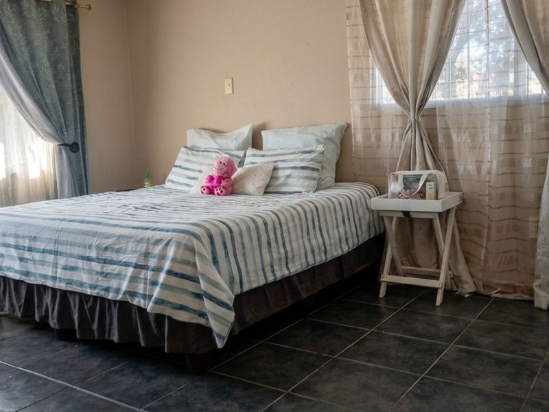 A bedroom featuring dark tiled flooring and dual window treatments, providing a neutral base for interior design updates.