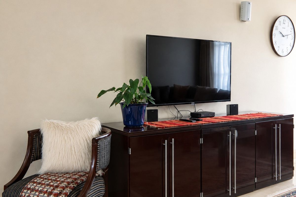 A well-maintained living room area featuring crown molding and tiled flooring, providing a clean and neutral backdrop for the space.