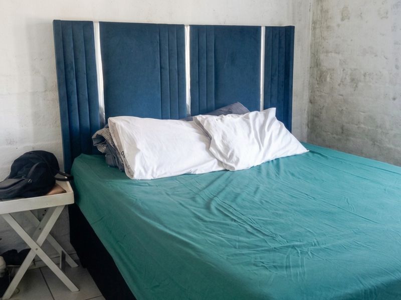 A bedroom featuring unfinished brick walls and security bars on the window, requiring cosmetic updates to improve the overall finish.
