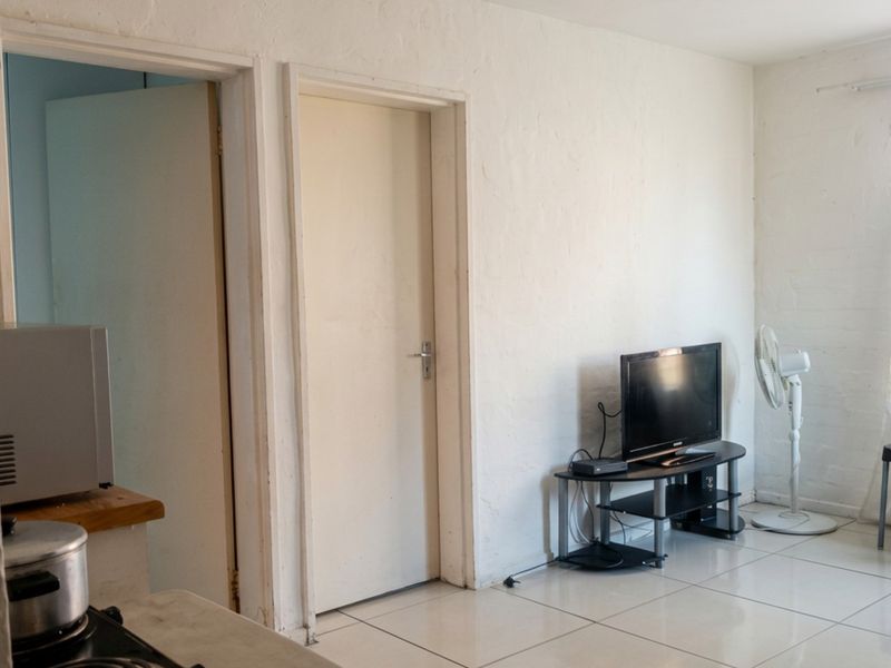 Open plan living area featuring tiled flooring and direct access to adjacent rooms, providing a functional layout with potential for cosmetic updates.