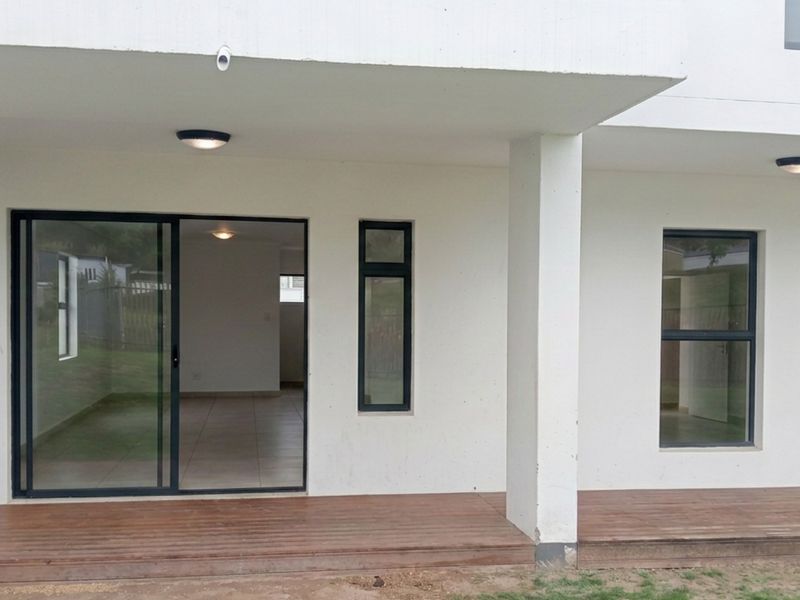 A covered patio area featuring timber decking, sliding glass doors, and modern aluminium window frames, providing seamless access to the interior living space.