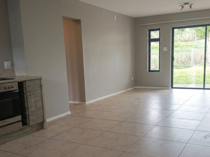 Open-plan living area featuring tiled flooring, a built-in oven and hob, and large sliding glass doors providing access to the garden.