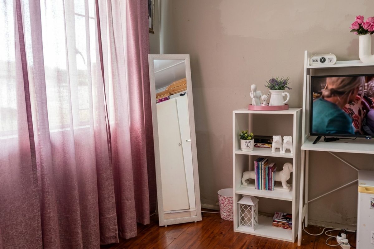A bedroom featuring warm timber flooring and a large window with natural light, providing a comfortable and functional living space.