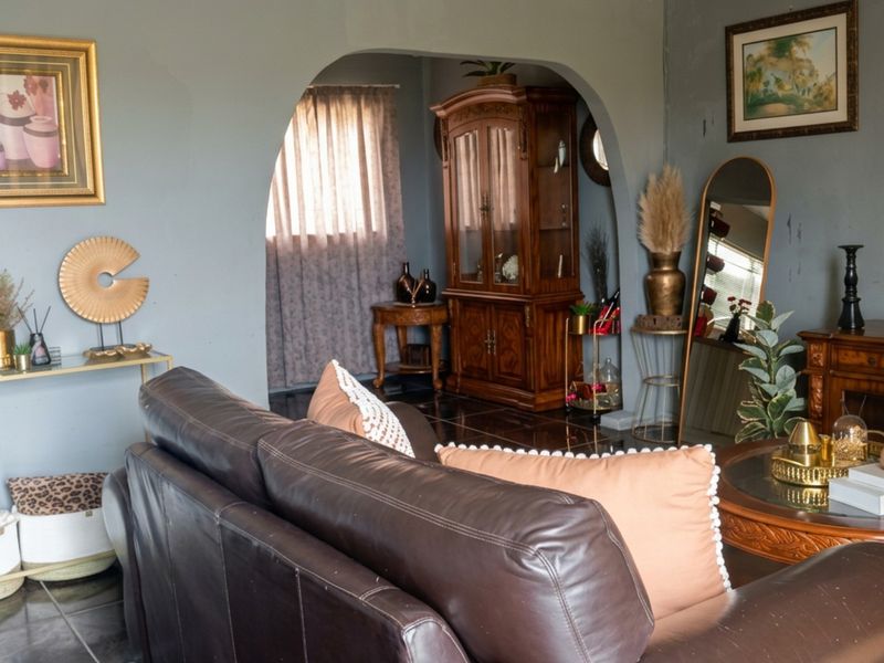 A living room featuring an arched doorway leading to an adjacent space, finished with dark tiled flooring.