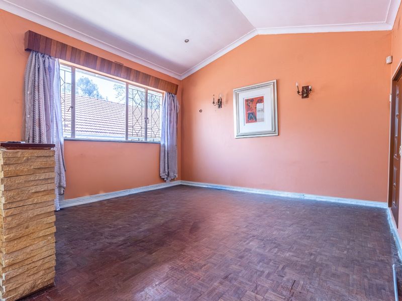 Spacious living room featuring parquet flooring, a vaulted ceiling, and a stone-clad feature wall, offering a blank canvas for modern interior design.