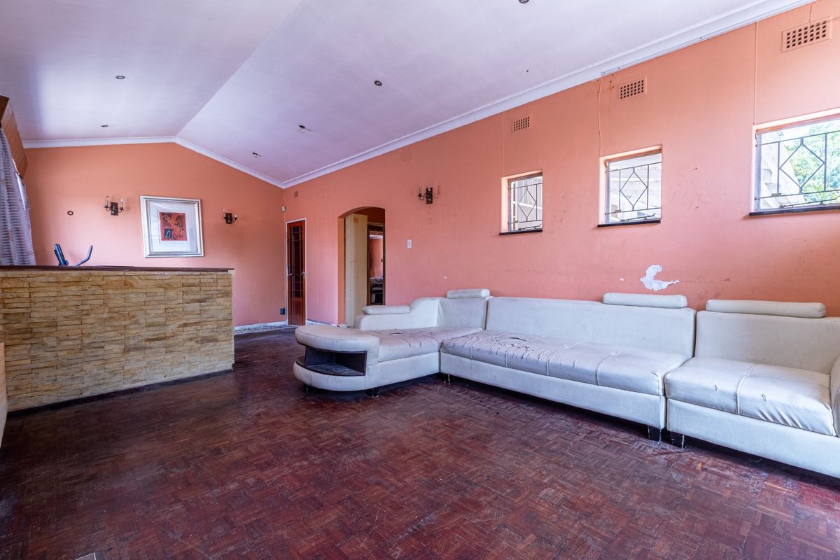 Spacious living room featuring parquet flooring, a stone-clad feature wall, and coved ceilings, offering a blank canvas for renovation and modernization.