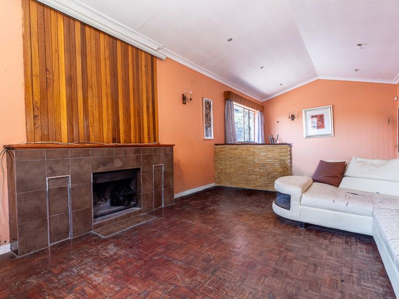 Living room featuring a tiled fireplace, wood paneling, and parquet flooring, with a built-in brick bar counter and vaulted ceilings.