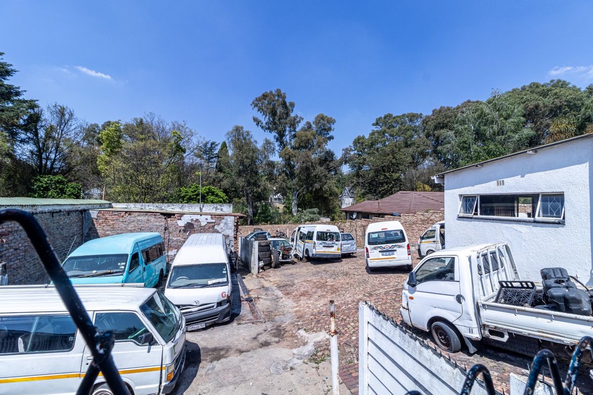 Rear exterior area featuring a paved yard enclosed by brick boundary walls, currently utilized for vehicle storage.