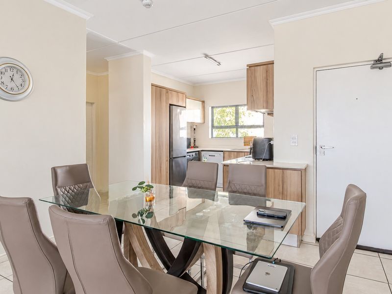 Open-plan dining area adjacent to a functional kitchen with built-in cabinetry and tiled flooring throughout.