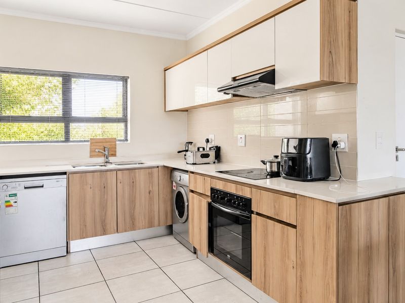 Modern kitchen featuring light wood-finish cabinetry, stone countertops, integrated appliances, and tiled flooring, offering a clean and functional workspace.