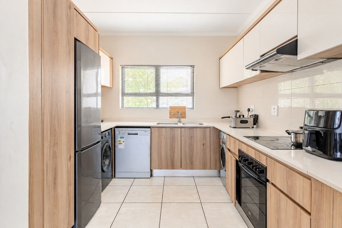 Modern kitchen featuring wood-grain cabinetry, stone countertops, integrated appliances, and tiled flooring, offering a clean and functional workspace.