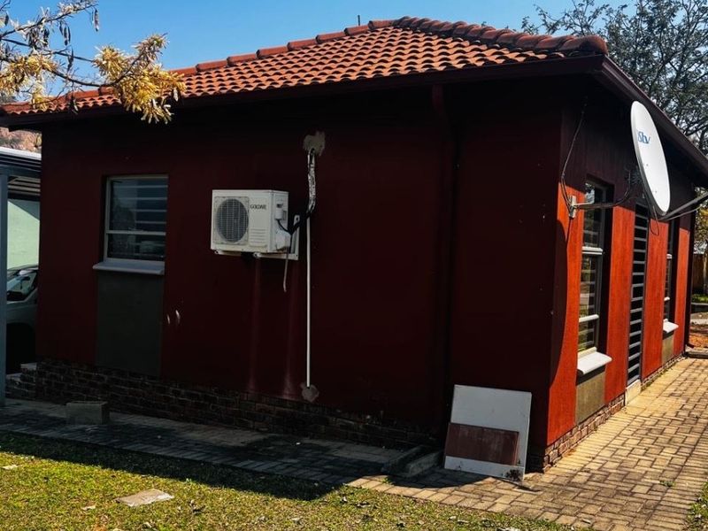Rear exterior view of the house featuring a terracotta tiled roof, brick plinth, and an installed air conditioning unit.