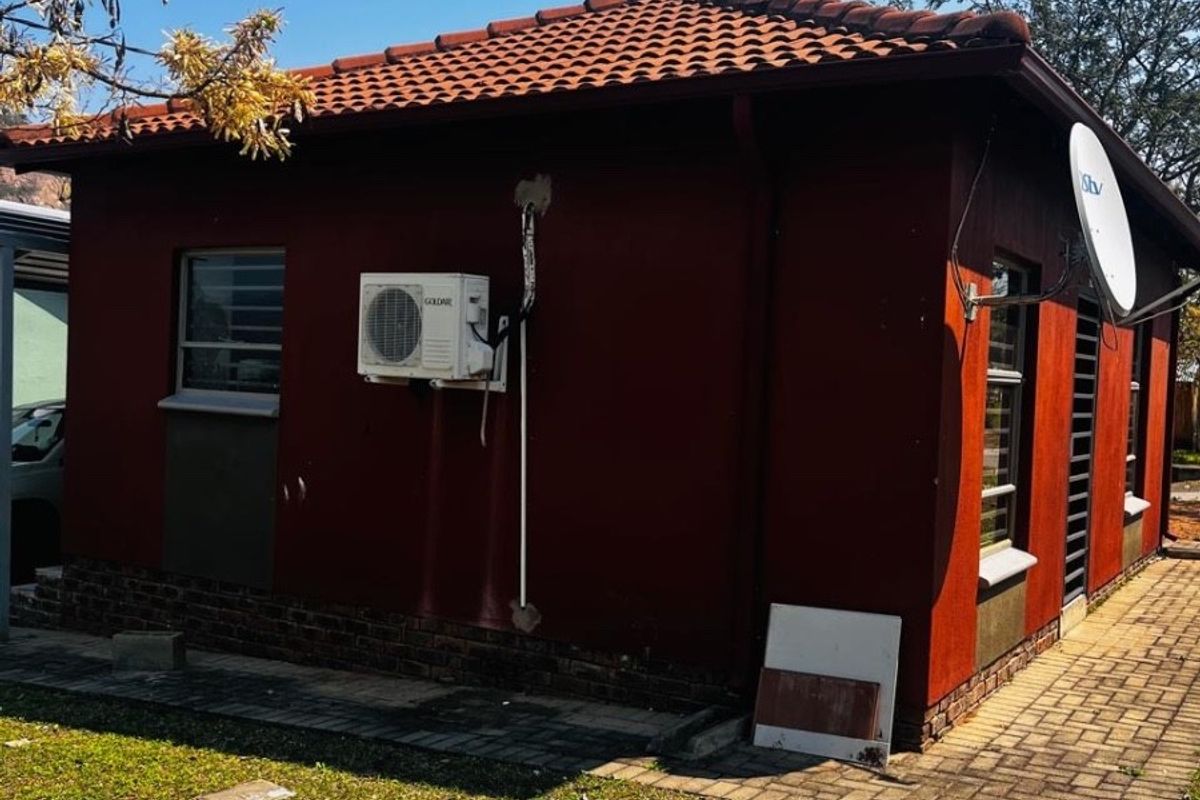 Rear exterior view of the house featuring a terracotta tiled roof, brick plinth, and an installed air conditioning unit.