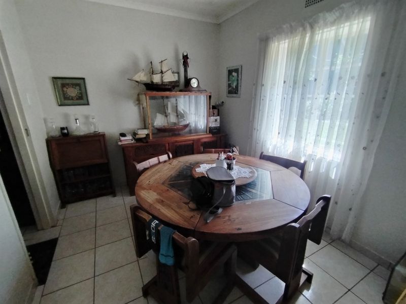 A functional dining room featuring tiled flooring and a large window, providing a bright and practical space for family meals.