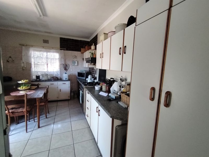 A functional kitchen featuring built-in cabinetry, laminate countertops, tiled flooring, and a built-in stove with an extractor fan.