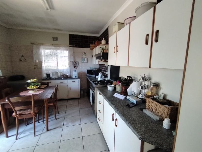 A functional kitchen featuring tiled flooring, built-in cabinetry, laminate countertops, and a tiled splashback, offering potential for modernization.
