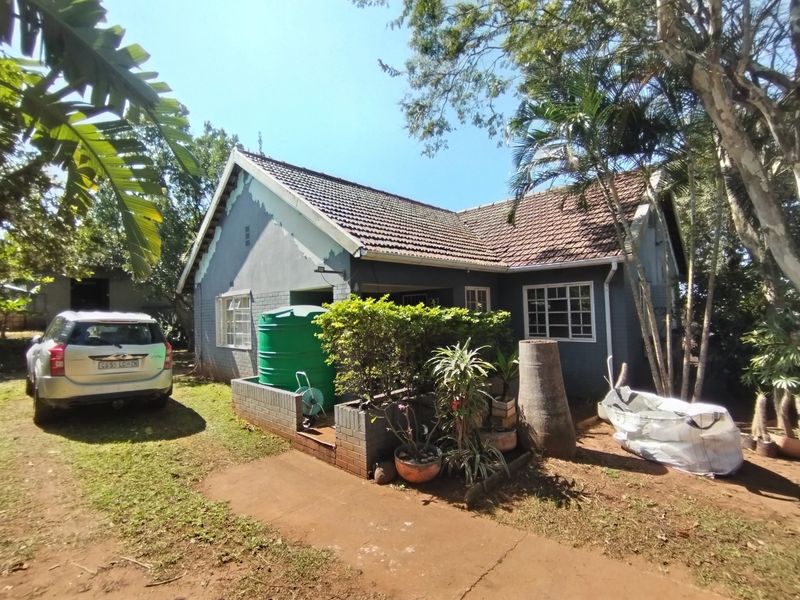 Front elevation of a single-story house featuring a tiled roof, grey painted brick exterior, and a water storage tank on the side.