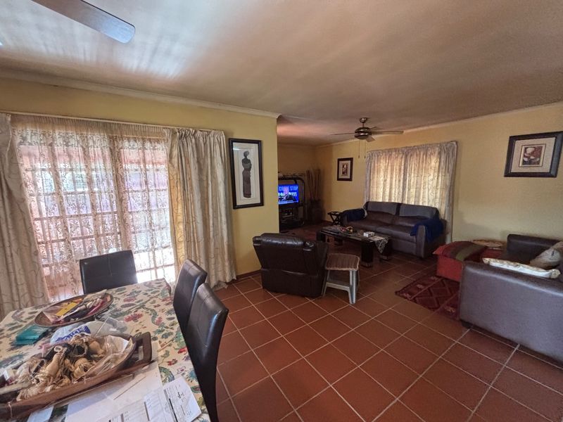 Spacious open-plan living and dining area featuring terracotta floor tiles, ceiling fans, and large sliding glass doors providing access to the exterior.