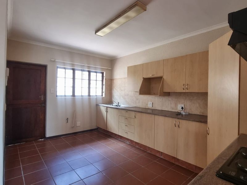 A functional kitchen featuring built-in cabinetry, laminate countertops, a stainless steel sink, and tiled flooring, offering a blank canvas for potential updates.
