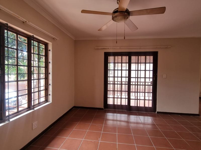Spacious living area featuring tiled flooring, a ceiling fan, and sliding glass doors leading to an outdoor space.