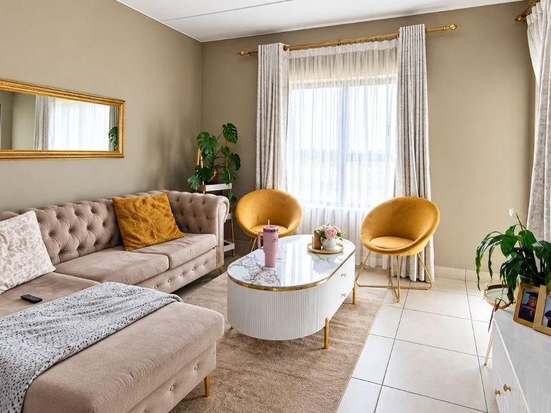 A well-maintained living room featuring neutral wall tones, tiled flooring, and large windows with installed curtain tracks, providing a bright and comfortable living space.