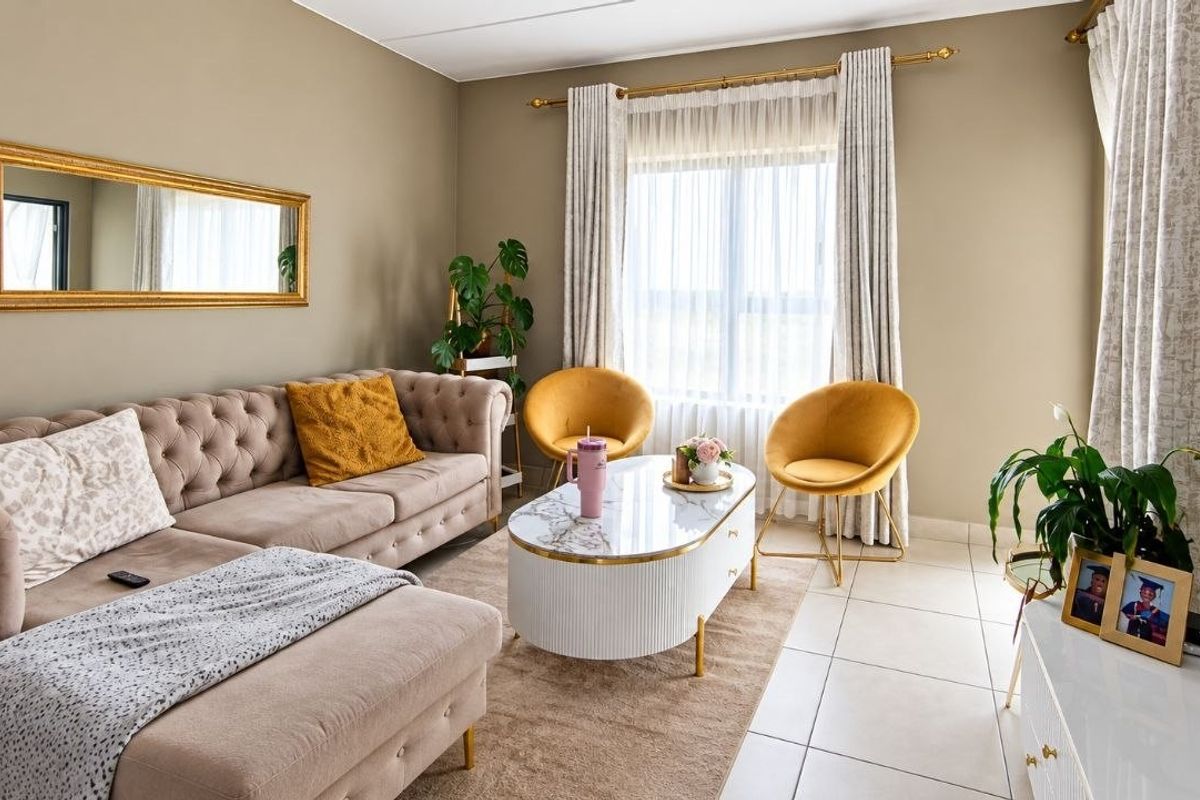 A well-maintained living room featuring neutral wall tones, tiled flooring, and large windows with installed curtain tracks, providing a bright and comfortable living space.