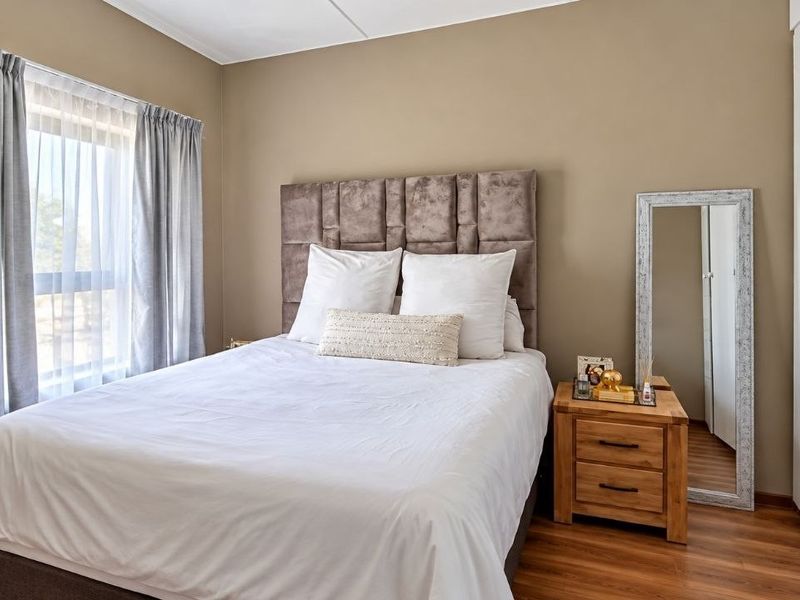 A well-maintained bedroom featuring laminate flooring, neutral wall tones, and a built-in wardrobe, offering a clean and comfortable living space.