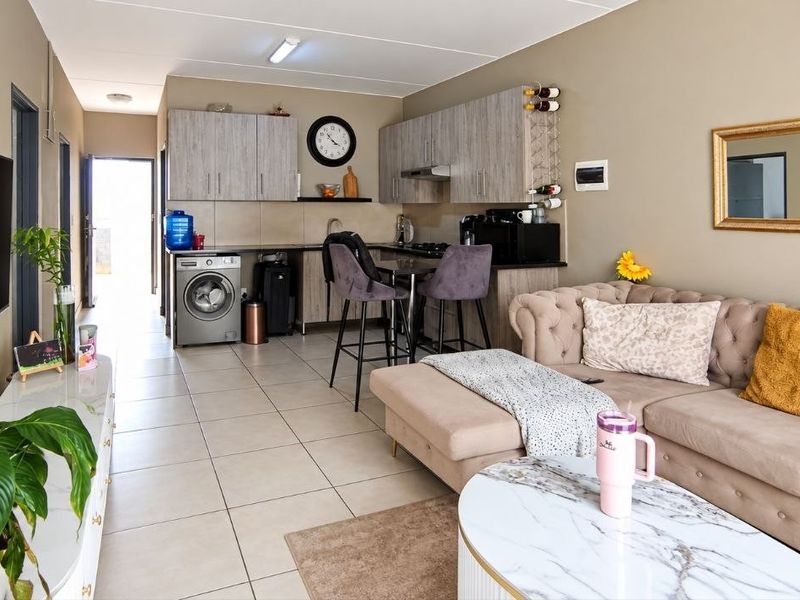 An open-plan living and kitchen area featuring tiled flooring, modern built-in cabinetry, and a functional layout connecting the kitchen to the lounge space.