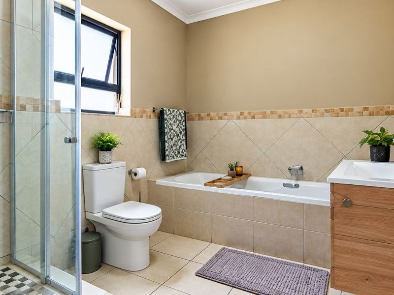 A well-maintained bathroom featuring a separate shower enclosure, bathtub, vanity cabinet with basin, and neutral wall and floor tiling.