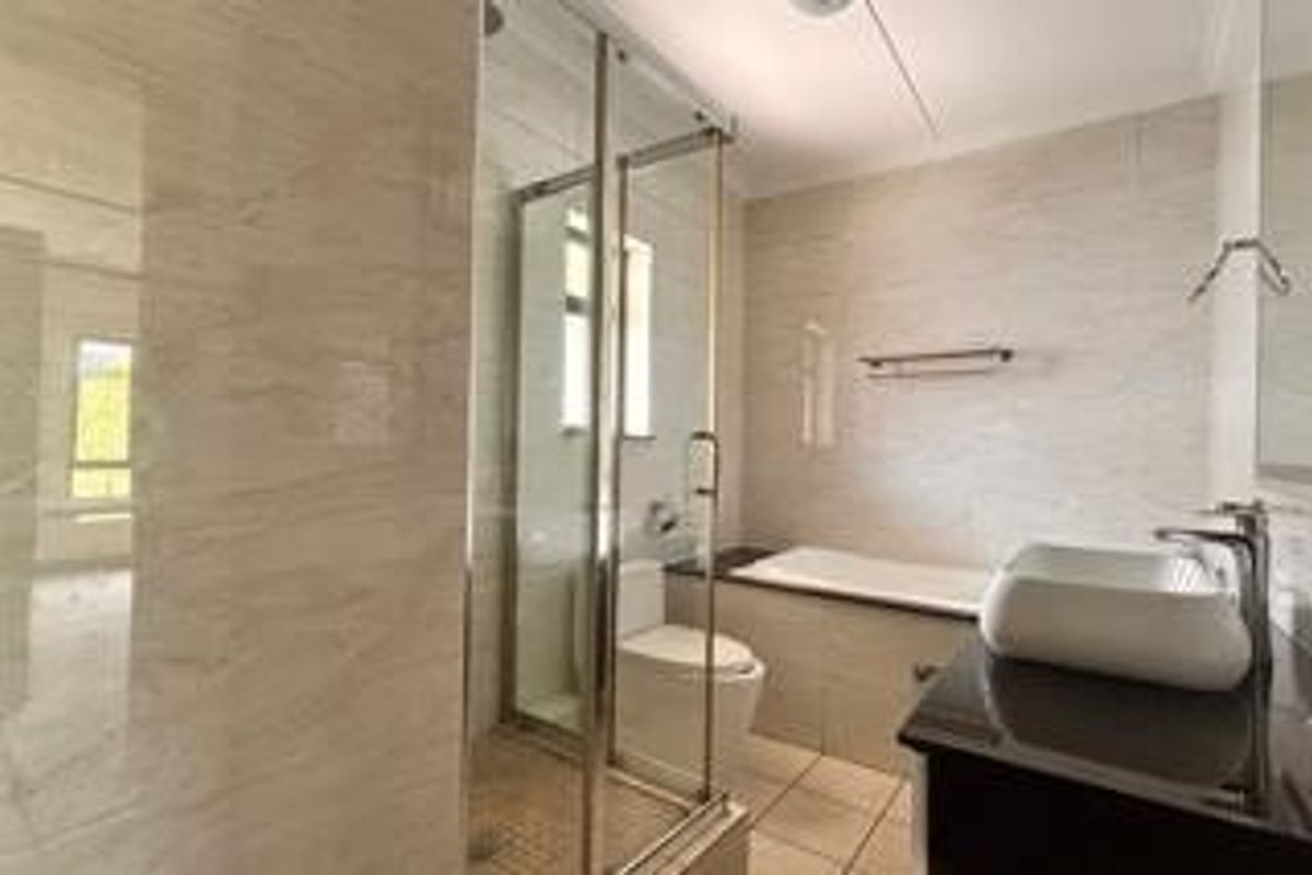 Modern bathroom featuring a glass shower enclosure, built-in bathtub, wall-mounted toilet, and a vessel sink set on a vanity cabinet with tiled finishes.