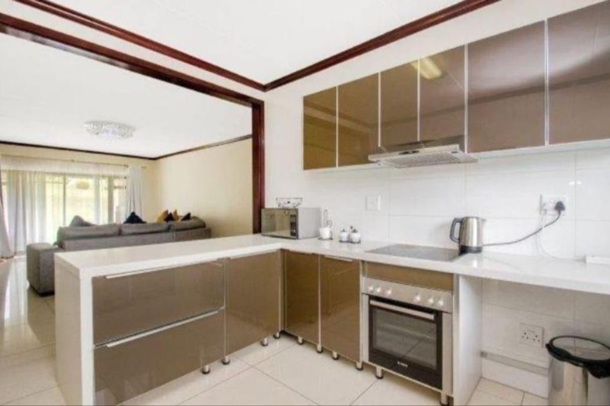 Modern open-plan kitchen featuring sleek high-gloss cabinetry, stone countertops, and integrated appliances, seamlessly flowing into the adjacent living area.
