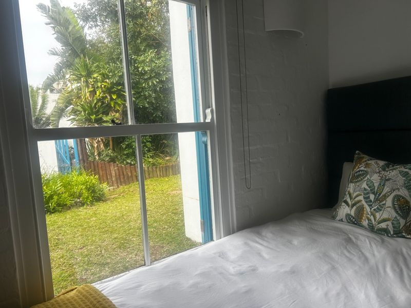 A bedroom featuring a classic sash window with views overlooking a private garden area.