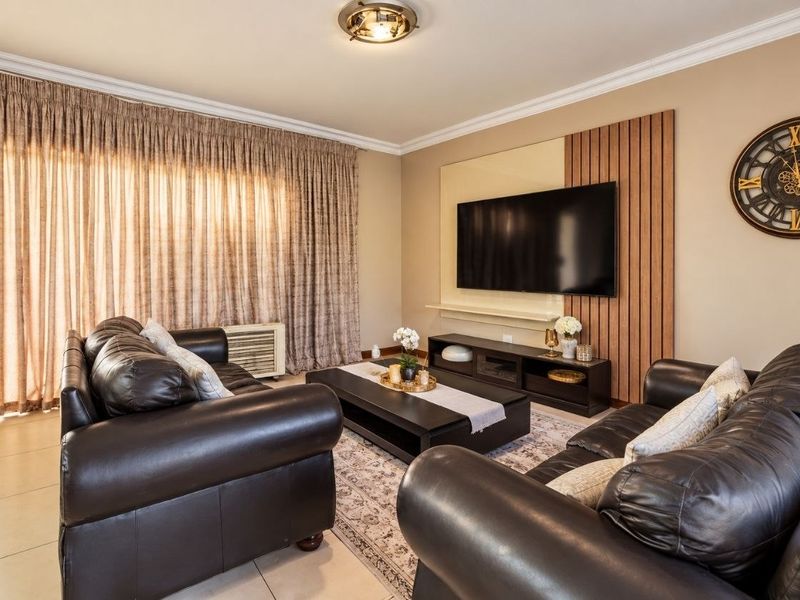 A comfortable living room featuring tiled floors, a decorative slatted timber wall panel, and large sliding glass doors providing access to the outdoor area.